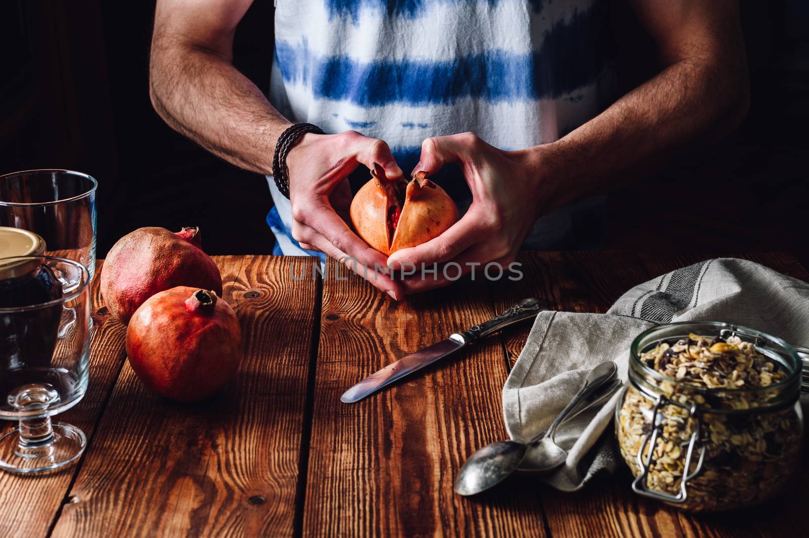 Man Opens Pomegranate. Series on Prepare Healthy Dessert with Pomegranate, Granola, Cream and Jam.