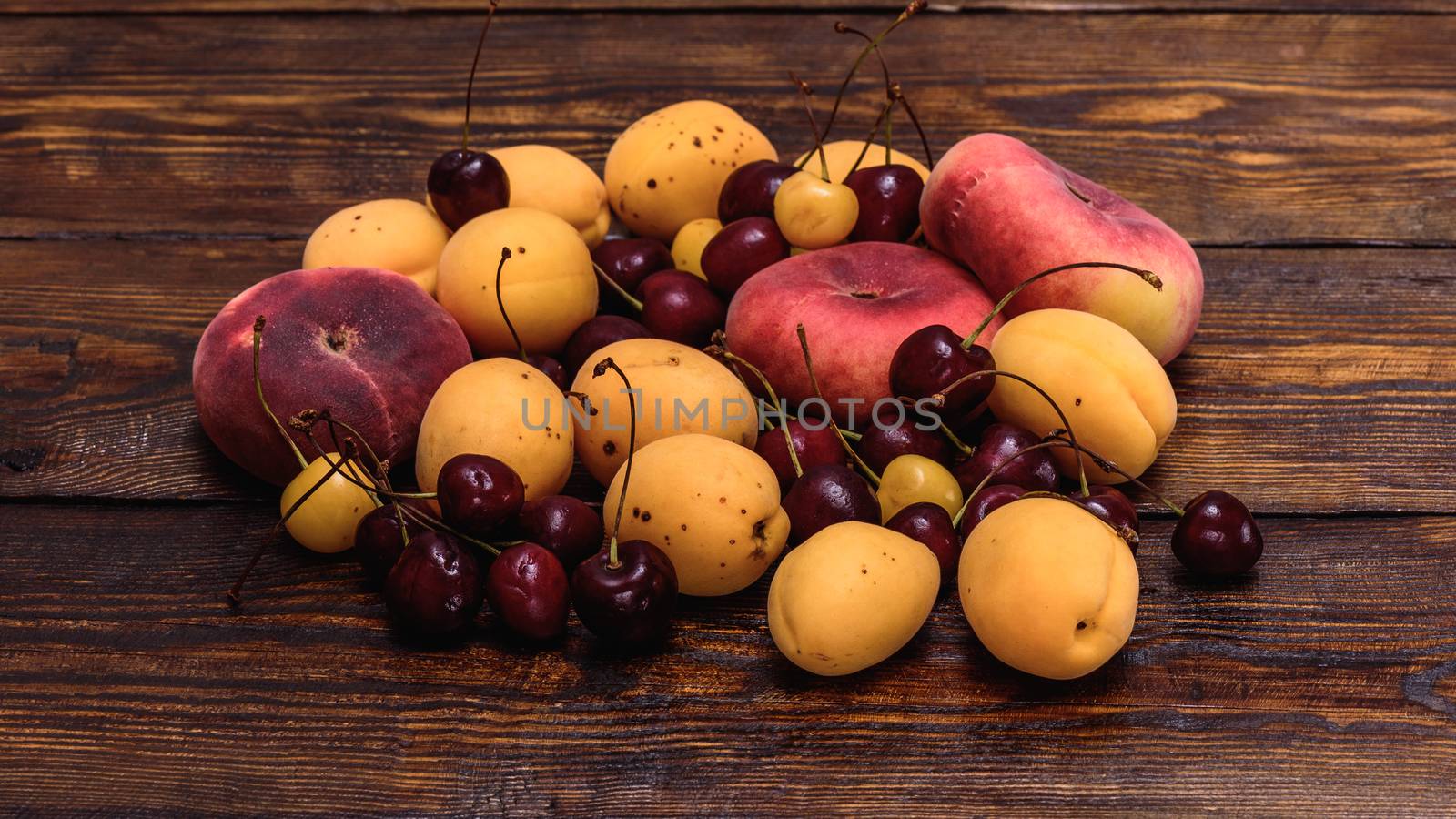 Fruits fig peaches, apricot and cherry on dark wooden table