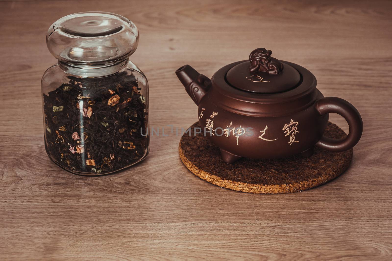 Asian teapot on stand and jar with fruit tea, inscription on the teapot: stone art treasures of God