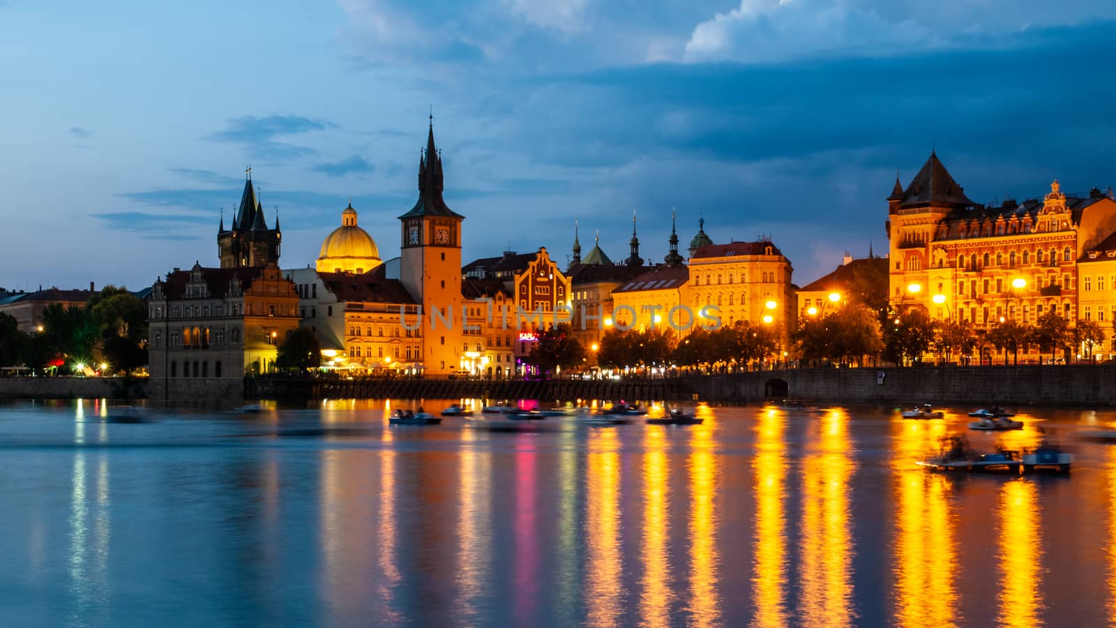 Historical buildings of Smetana Embankment reflected in the water of Vltava River on summer evening. Prague, Czech Republic.