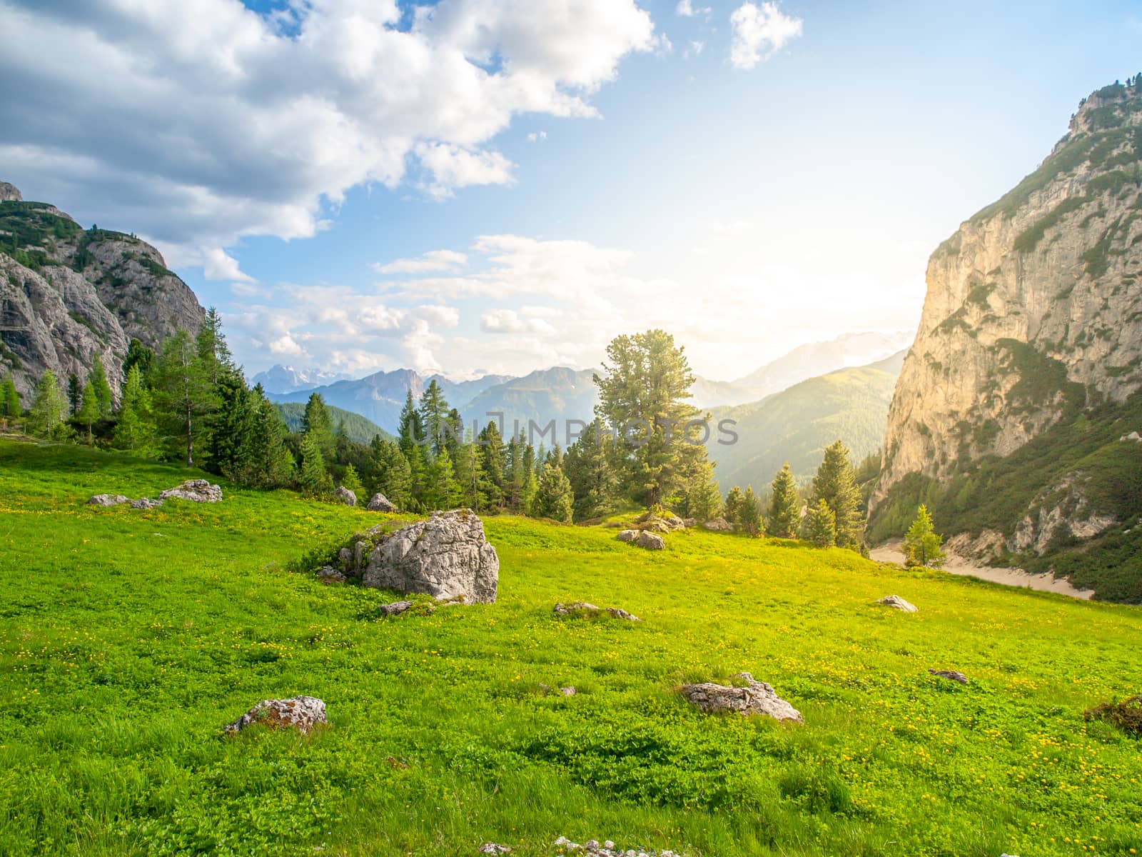 Landscape of Dolomites near Passo Falzarego. With green meadows, blue sky, white clouds and rocky mountains.