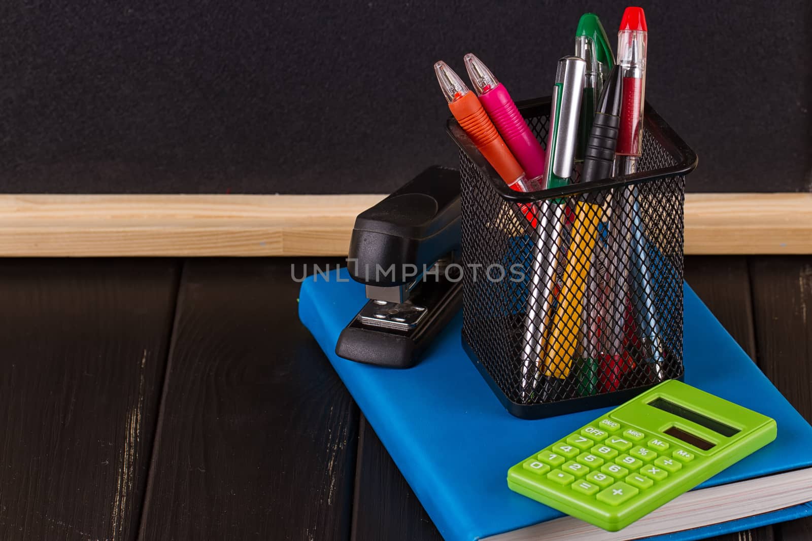 Stationery: pens, pen holder, diary on a black background