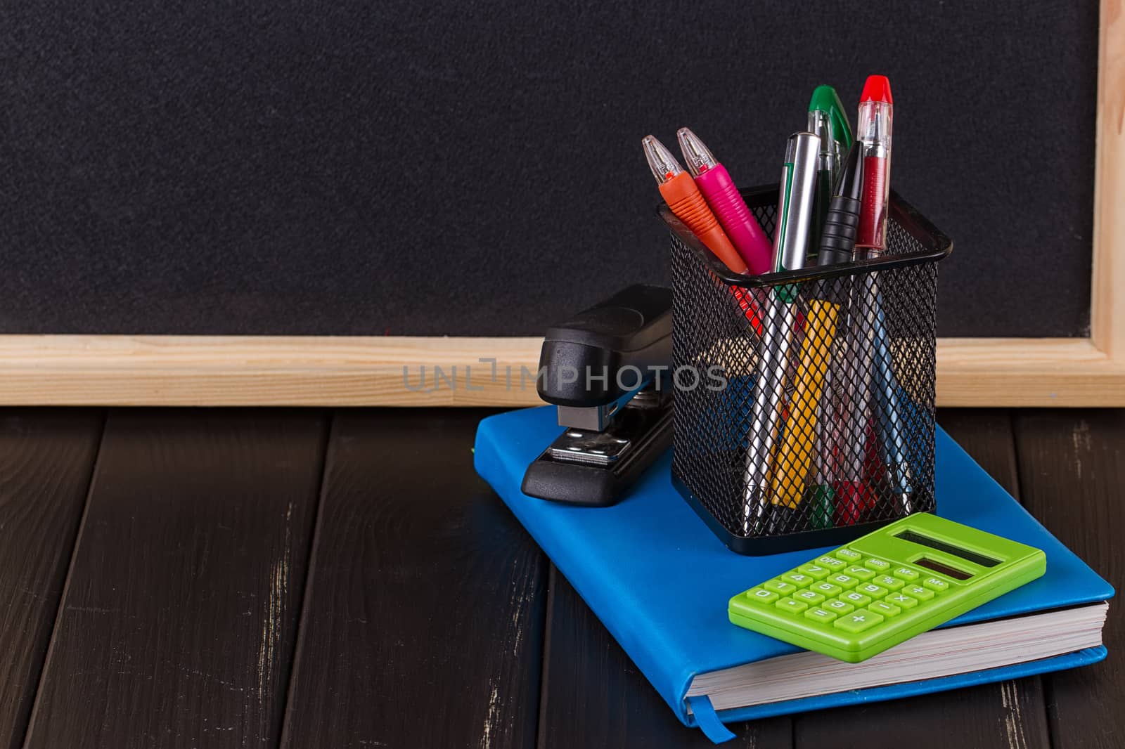 Stationery: pens, pen holder, diary on a black background