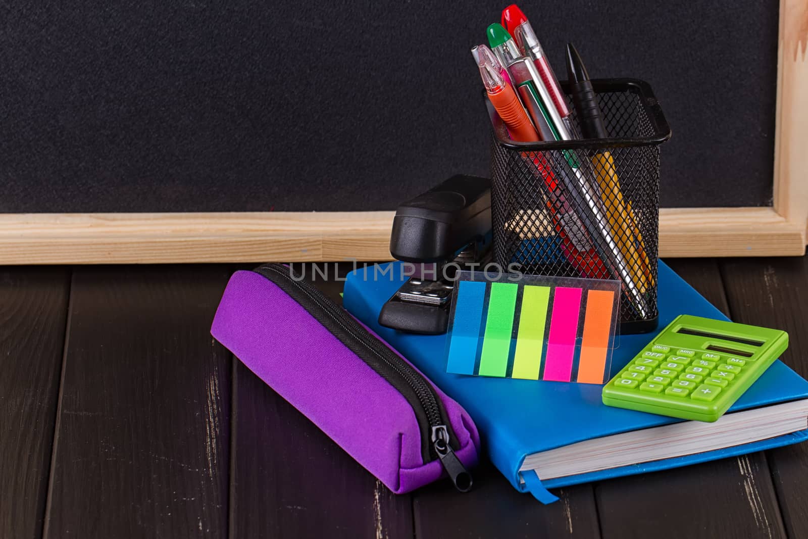 Stationery: pens, pen holder, diary on a black background