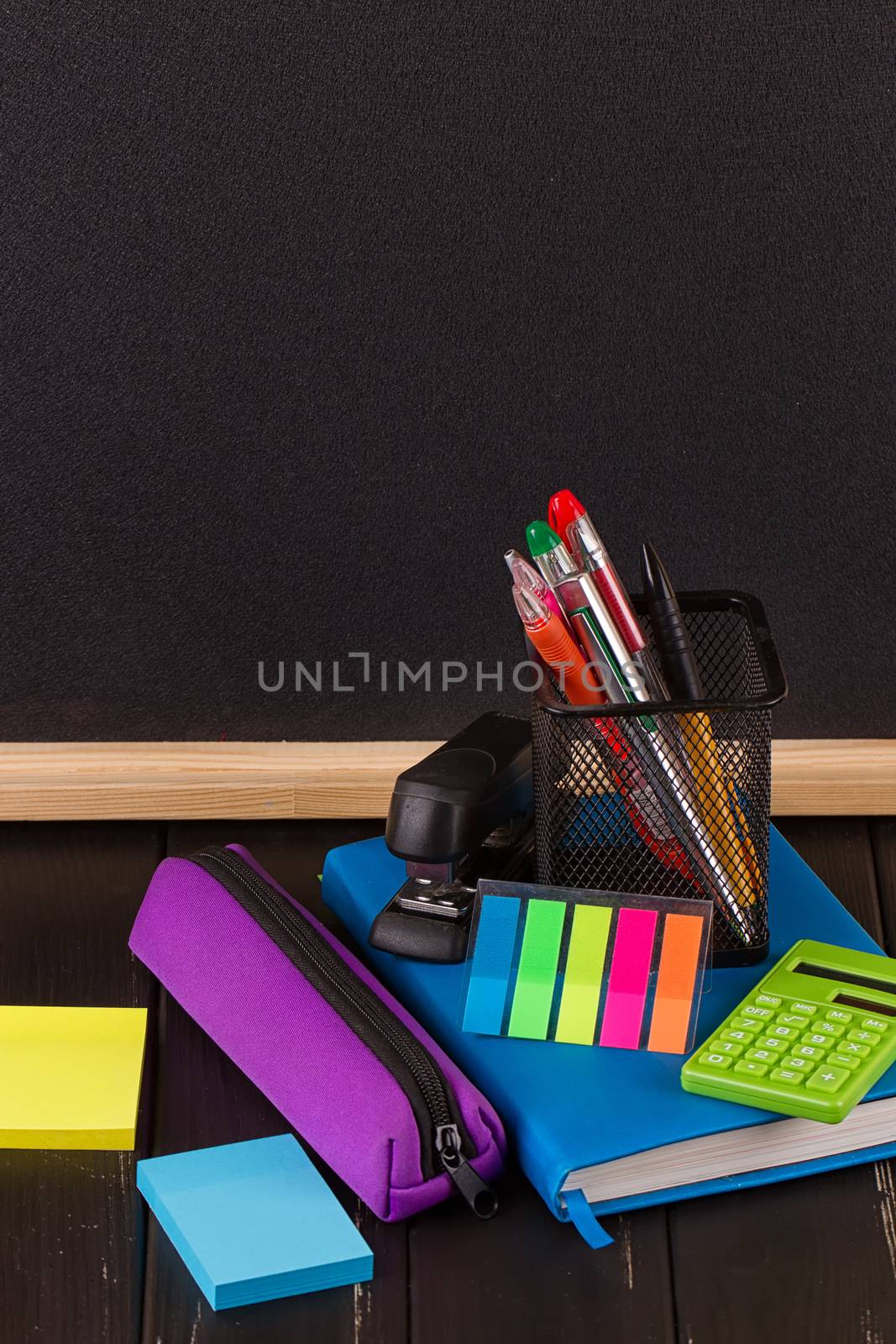 Stationery: pens, pen holder, diary on a black background