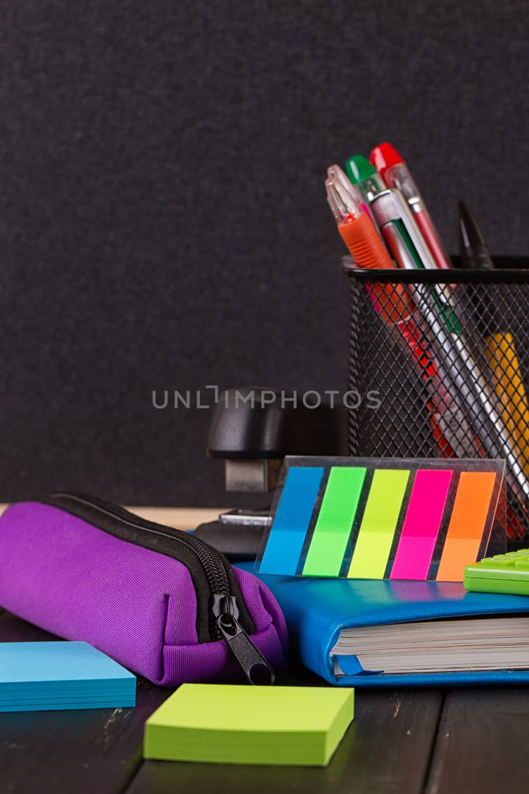 Stationery: pens, pen holder, diary on a black background