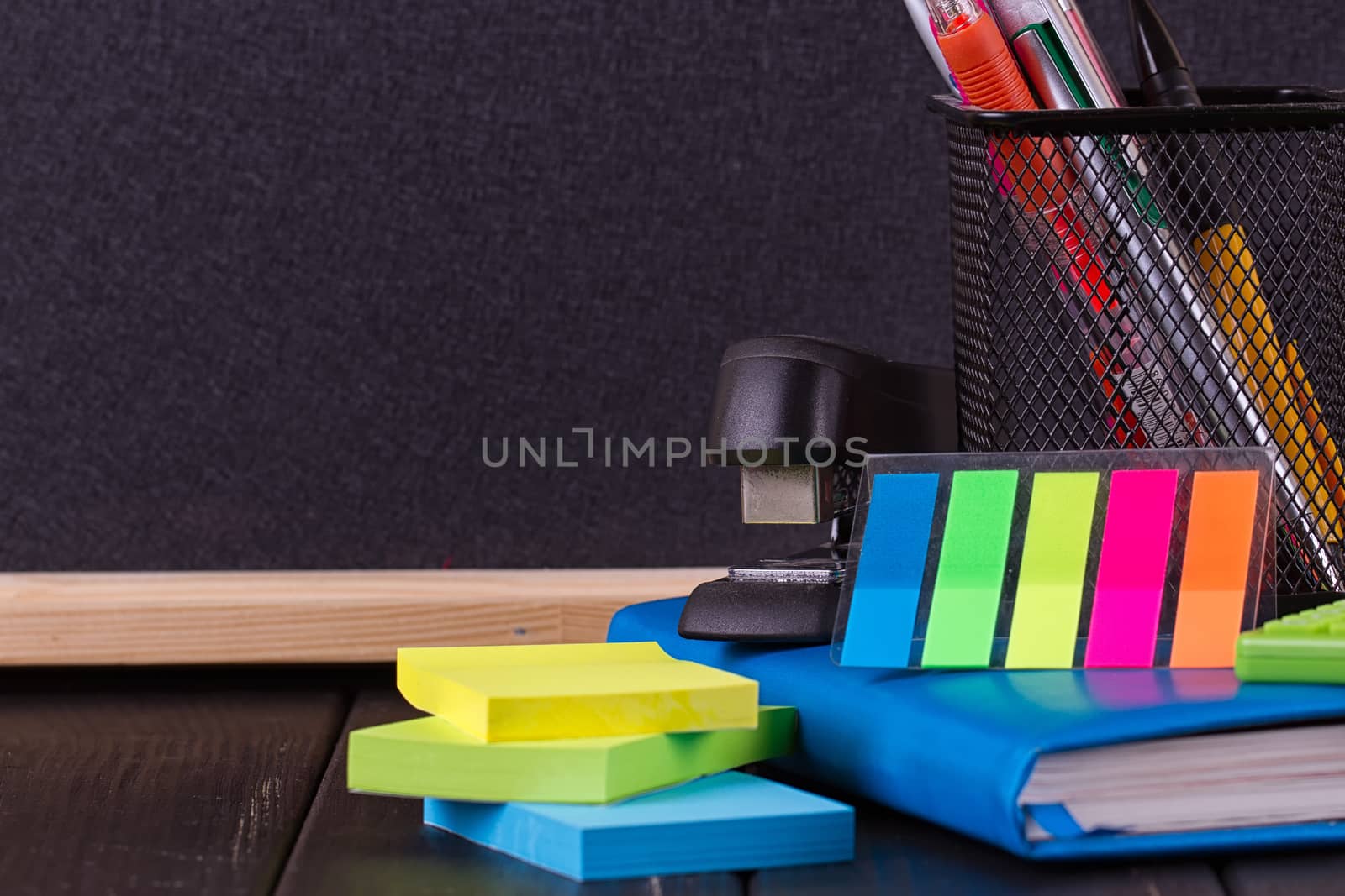 Stationery: pens, pen holder, diary on a black background