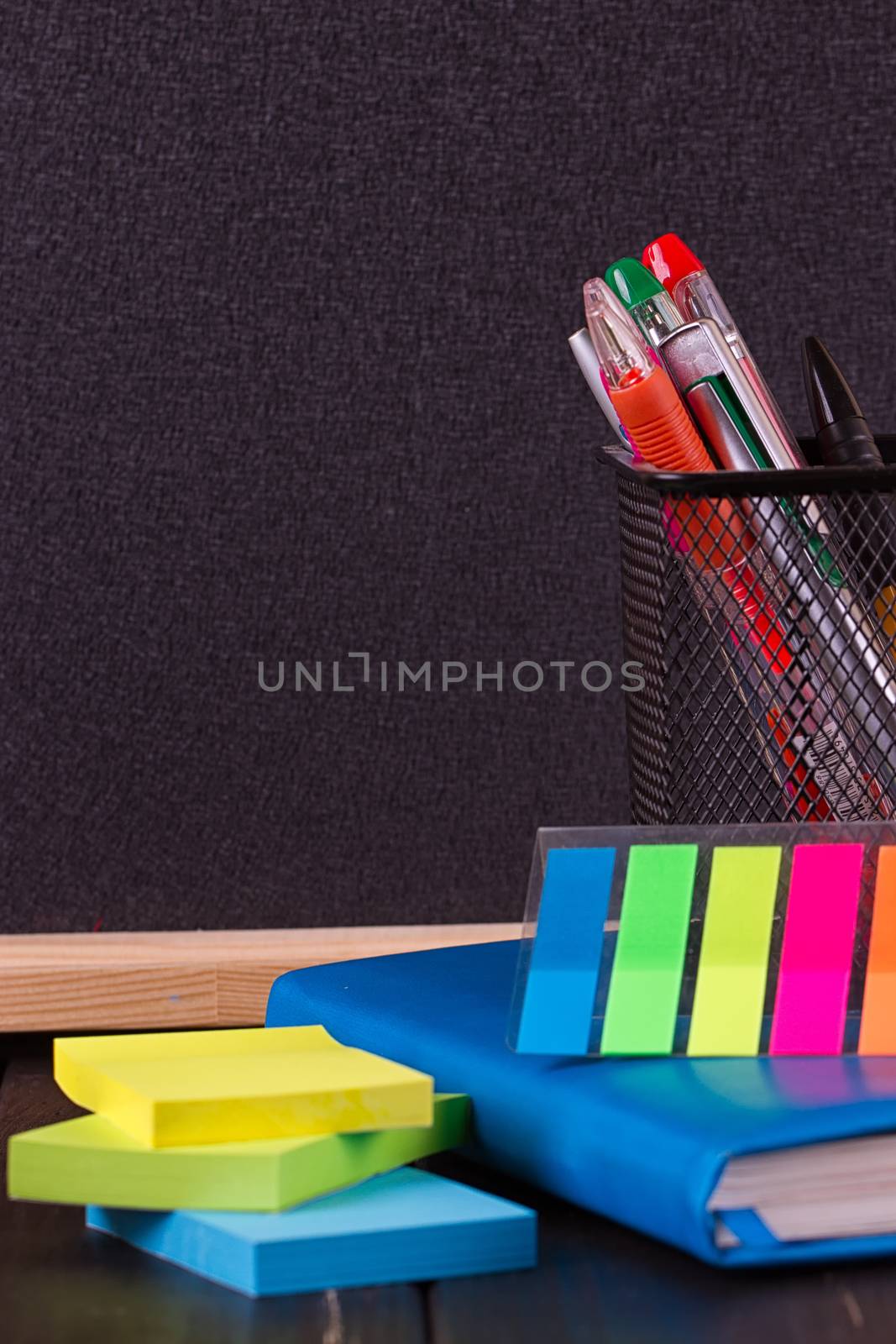 Stationery: pens, pen holder, diary on a black background