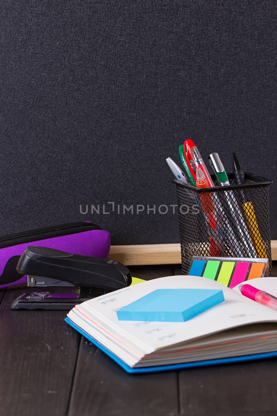Stationery: pens, pen holder, diary on a black background
