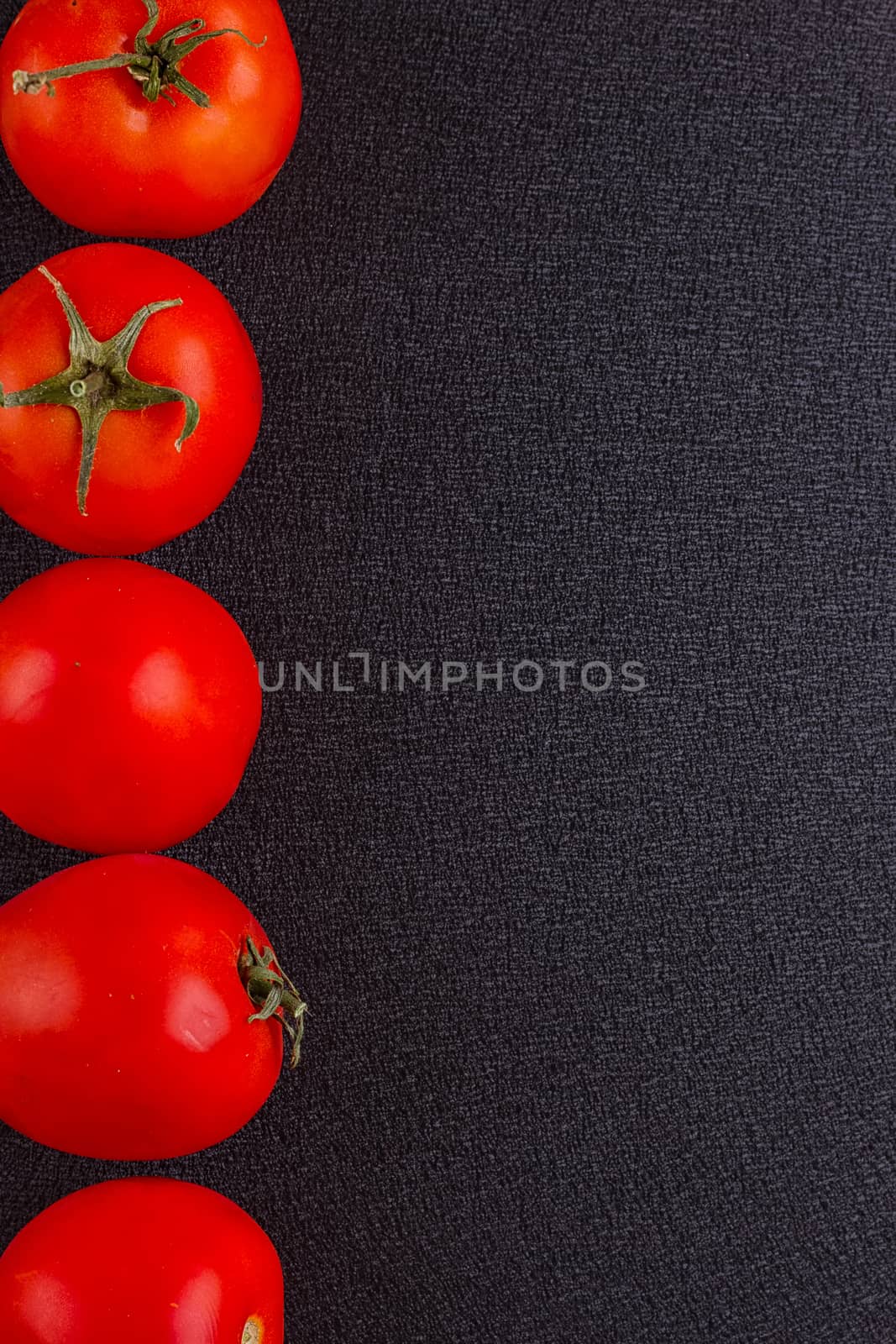 red tomatoes on black background. top view