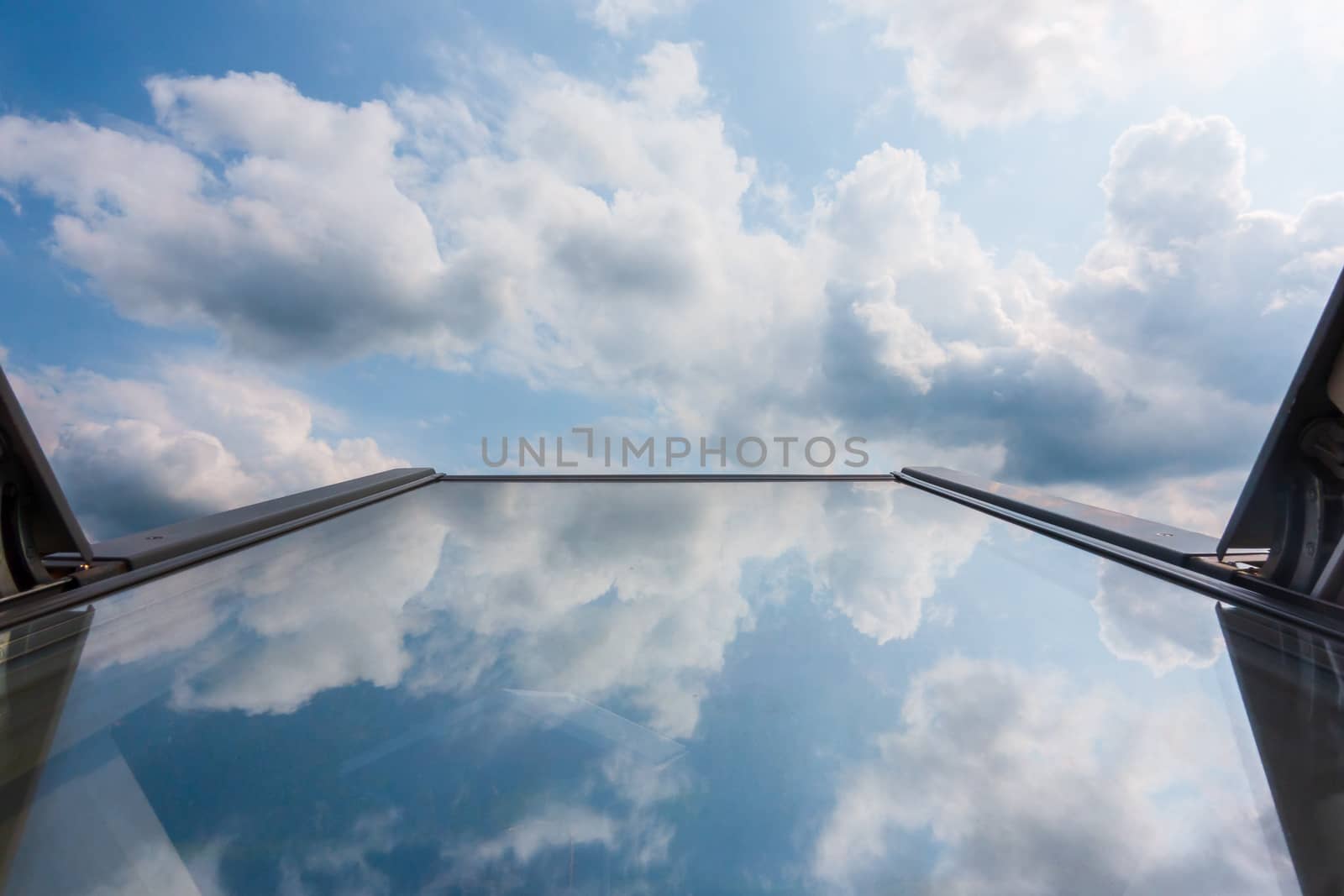 clouds reflected in roof window glass, tilted up against the sky, family house, home, clouds are ominous and a storm in coming, insurance and home security concept