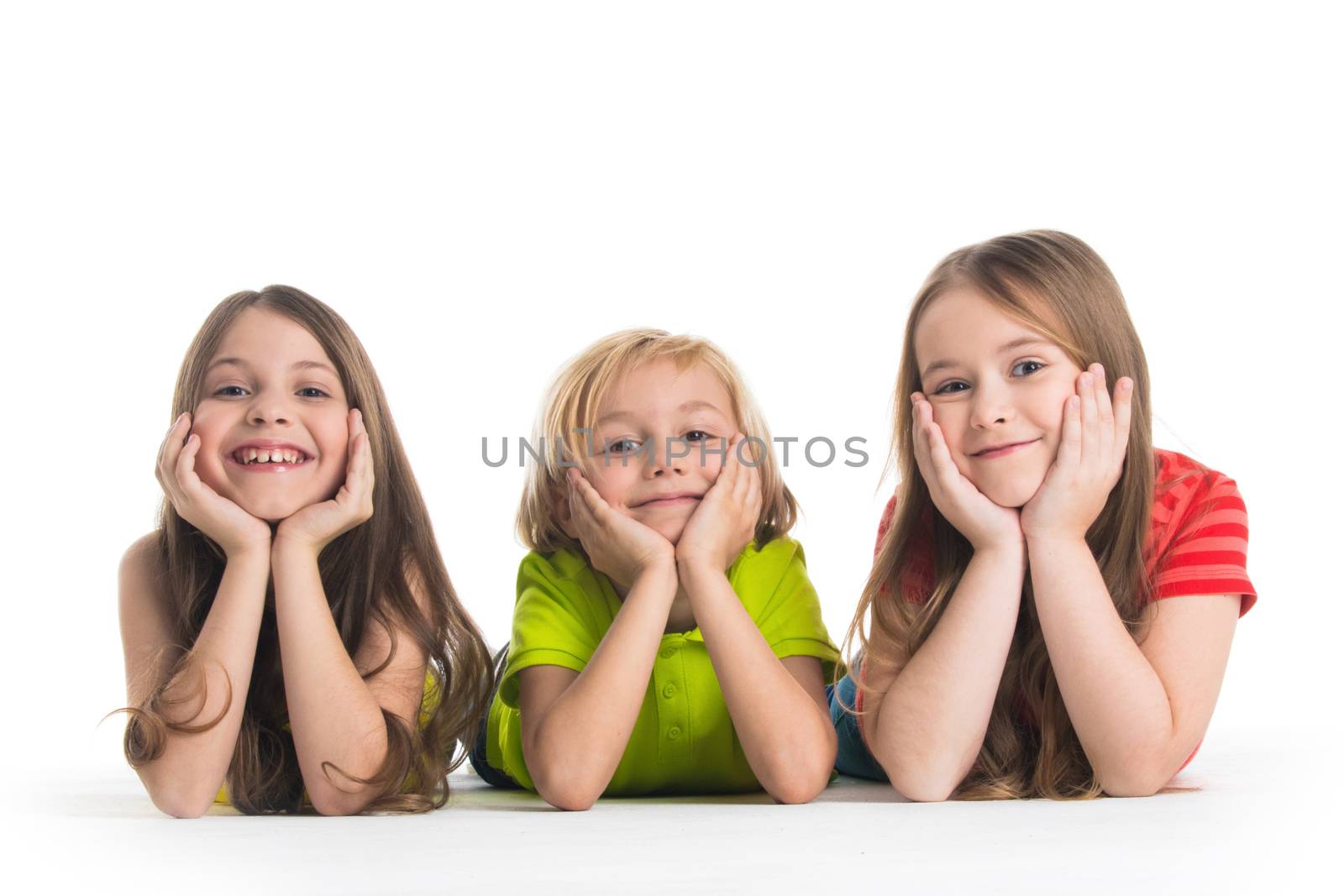 Happy smiling three children in colorful clothes laying on floor isolated on white background
