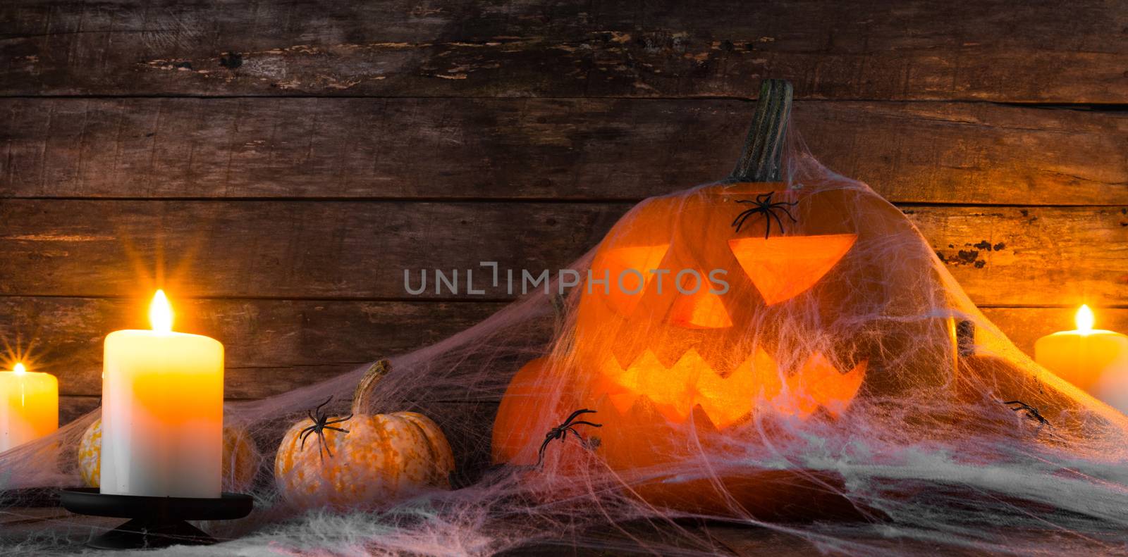 Jack O Lantern Halloween pumpkin, spiders on web and burning candles