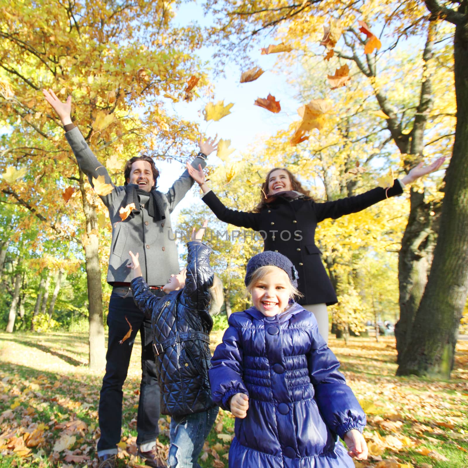 Happy family playing with autumn leaves by ALotOfPeople