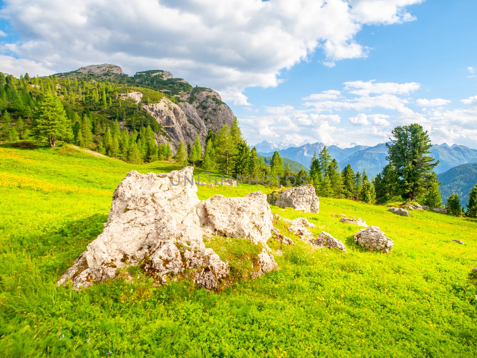 Landscape of Dolomites near Passo Falzarego. With green meadows, blue sky, white clouds and rocky mountains.