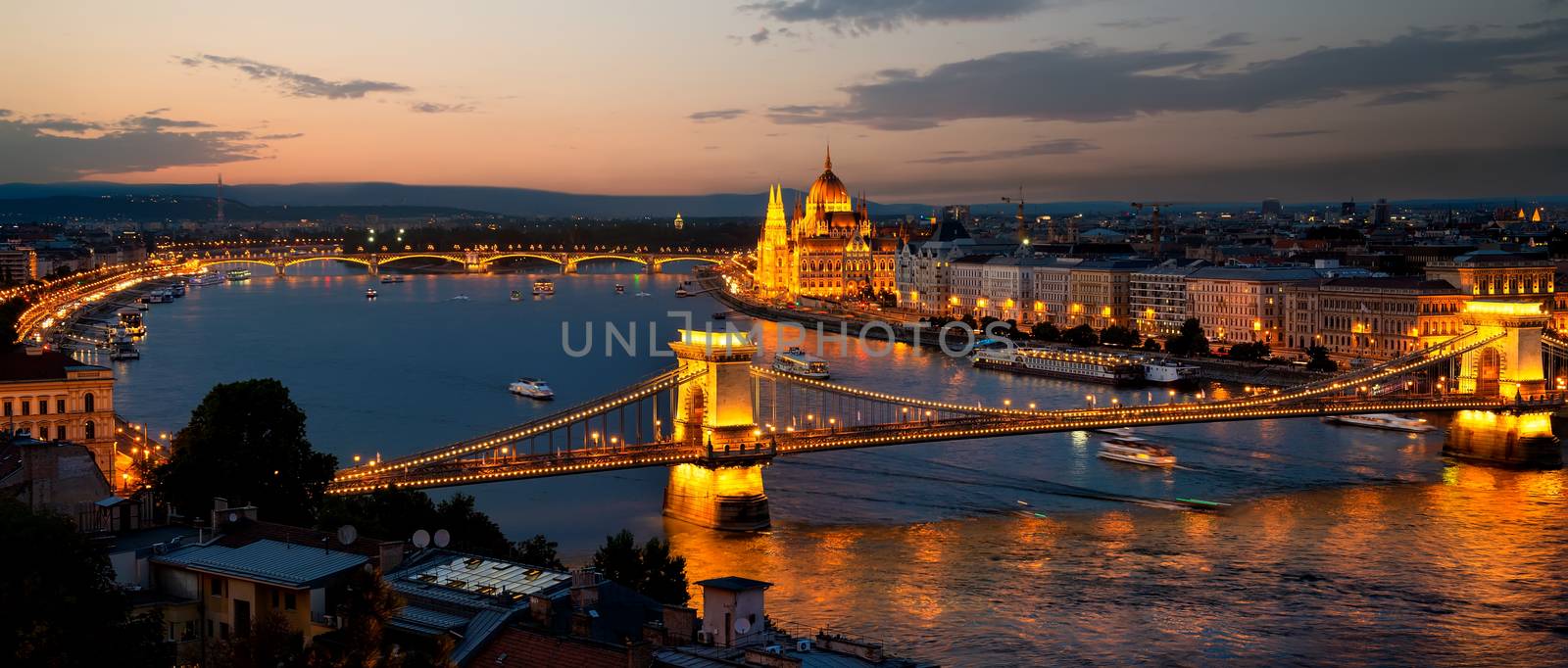 Parliament and bridges of Budapest illuminated in evening, Hungary