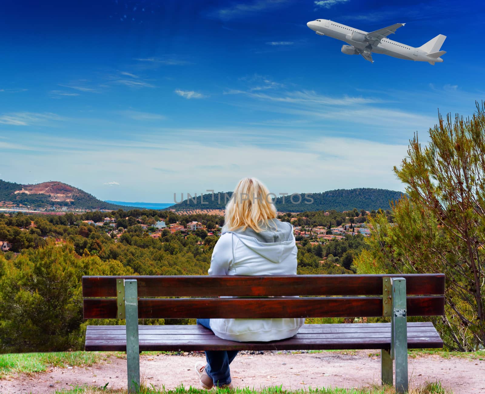 Woman sitting on a bench with panoramic view over Paguera towards bay of Palma, Mallorca in Spain.