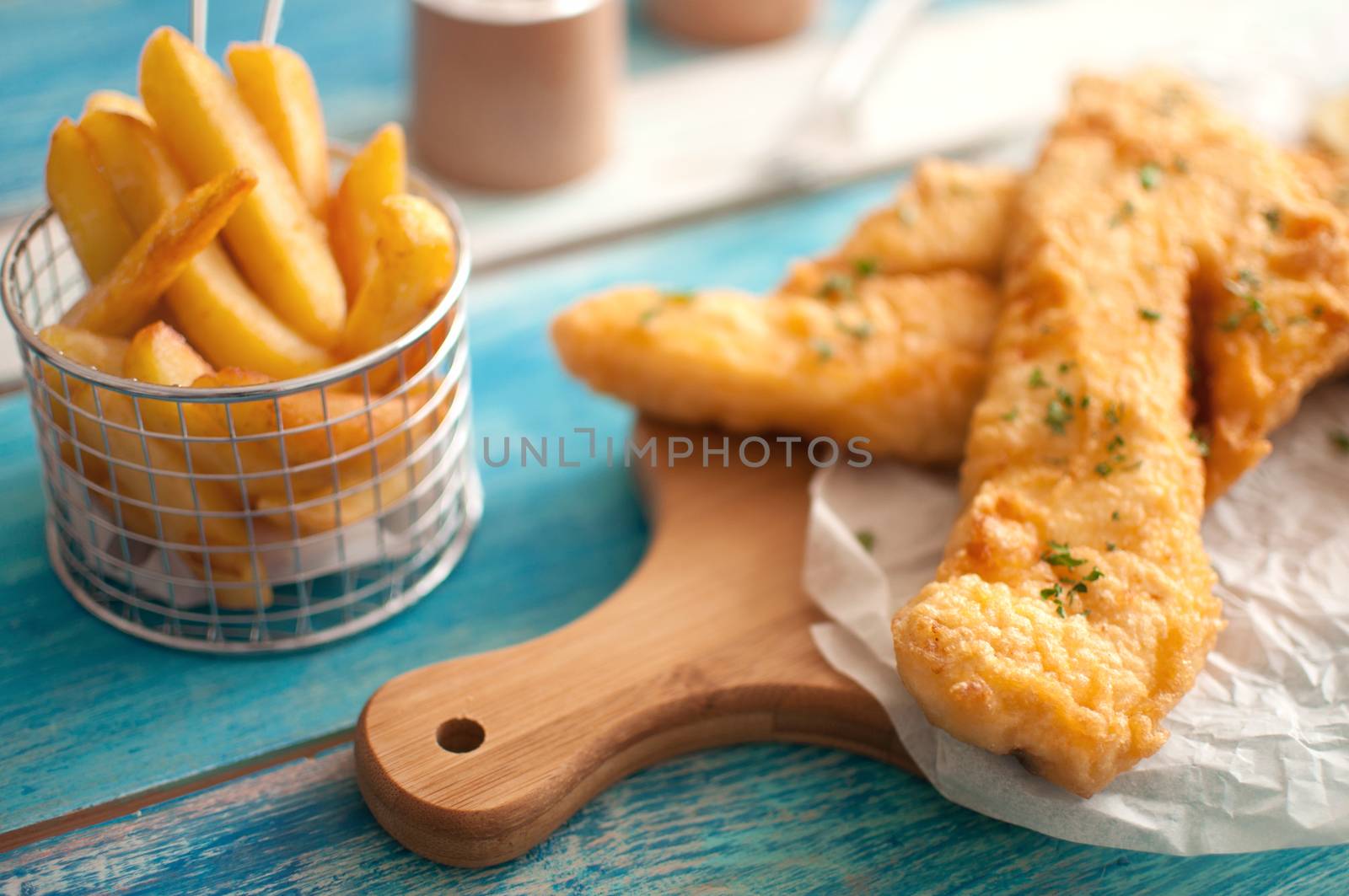 Two pieces of cod fried in batter with chips in a basket