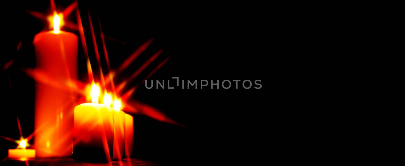 Set of lighting candles in a row on dark background