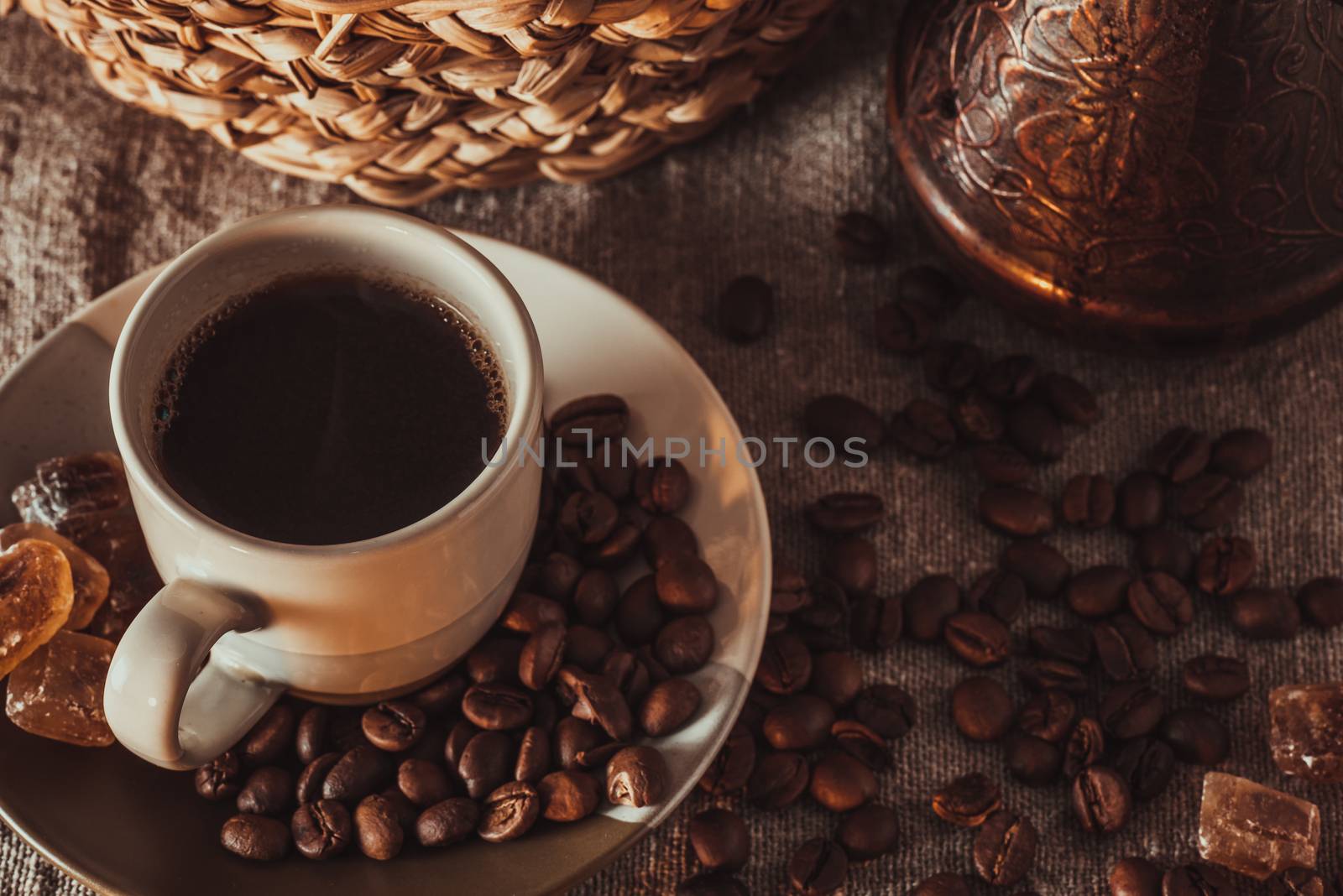 Cup of coffee on textile with beans, dark candy sugar, pots, basket and cake by Seva_blsv