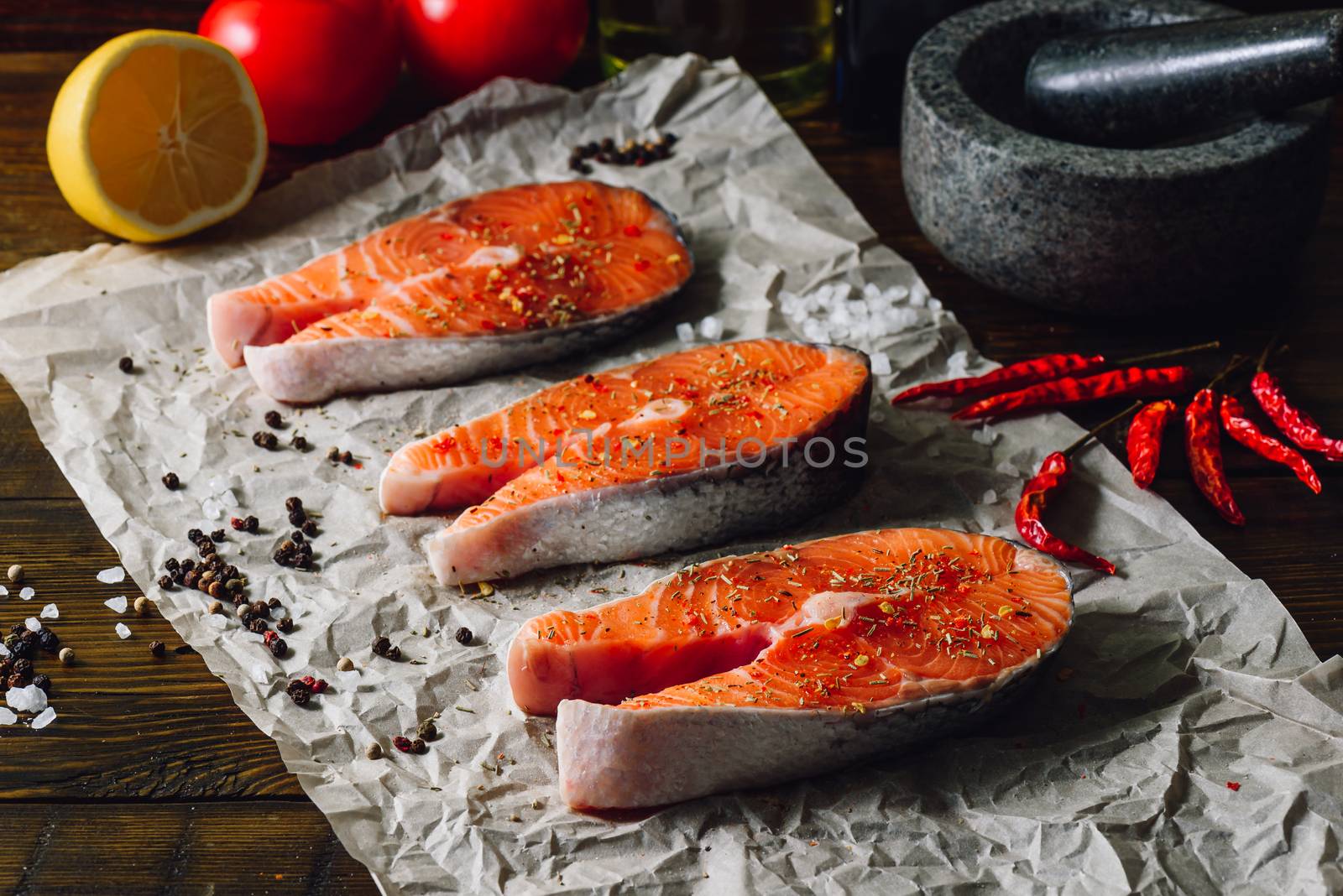 Three Salmon Steaks Prepared for Cooking with Chili Peppers and Other Spices.