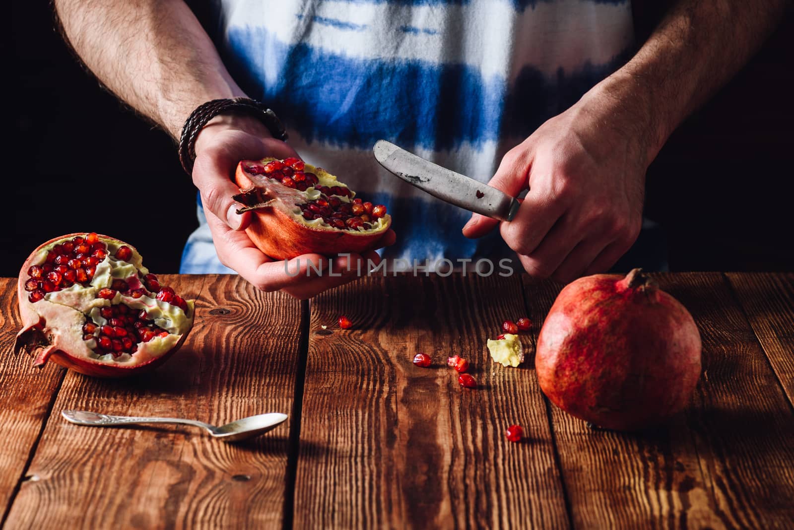 Pomegranate Half and Knife in Human Hands.