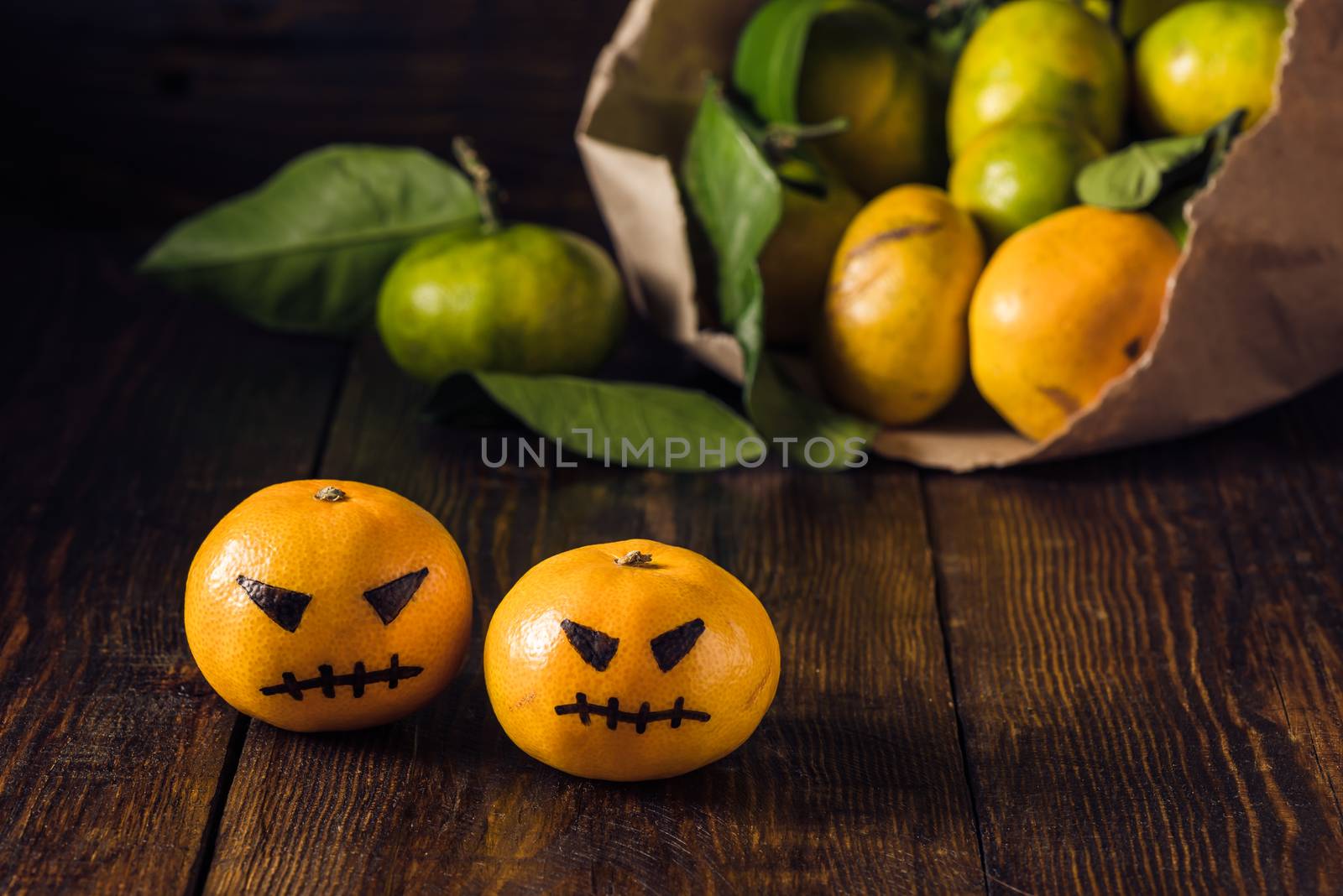 Two scary tangerines for Halloween and bunch of tangerines on background