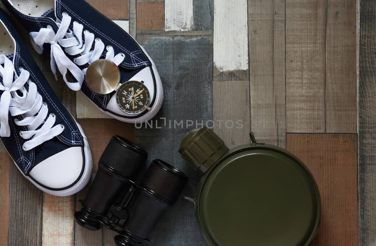 Pair of keds on color wooden background near compass and binoculars