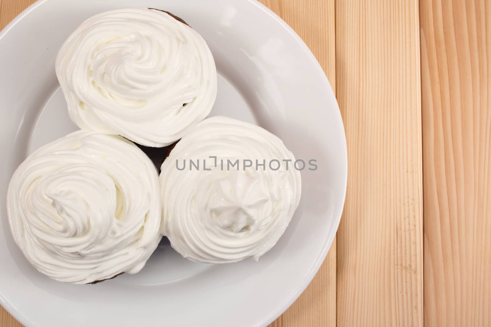 Muffins with cream on top of it sitting on bright wooden table