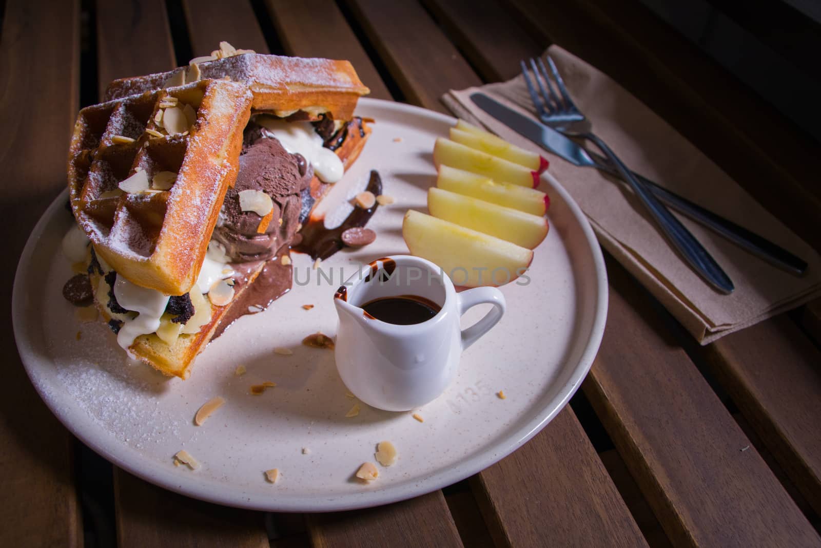 Waffle with chocolate sauce and chocolate icecream with brownie and wipcream and apple on white plate