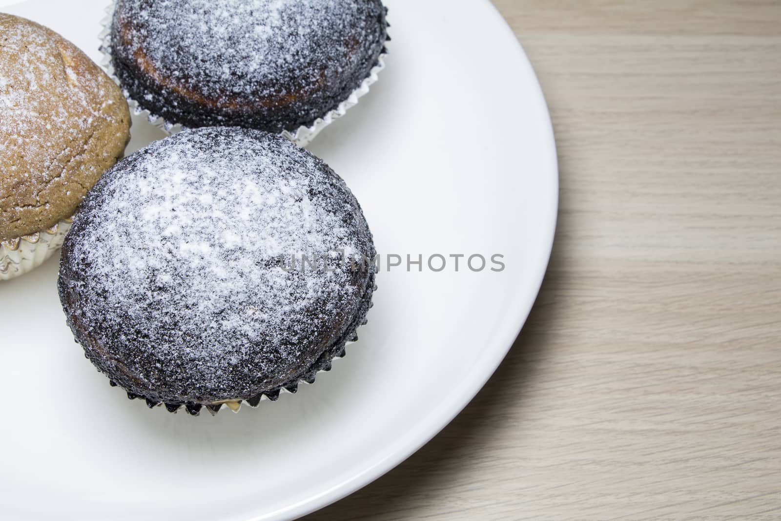 Close up on Muffin cake with white plate isolate on wooden Table