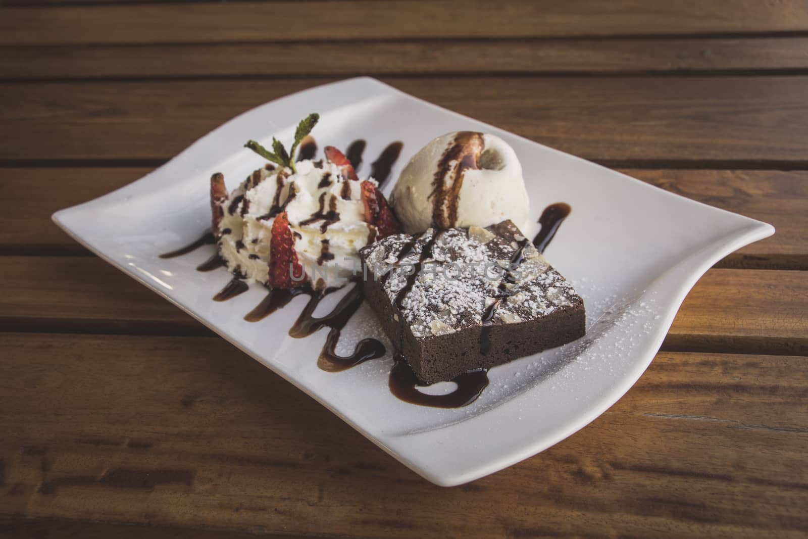 Chocolate brownies With whip cream and ice cream isolate on wood table