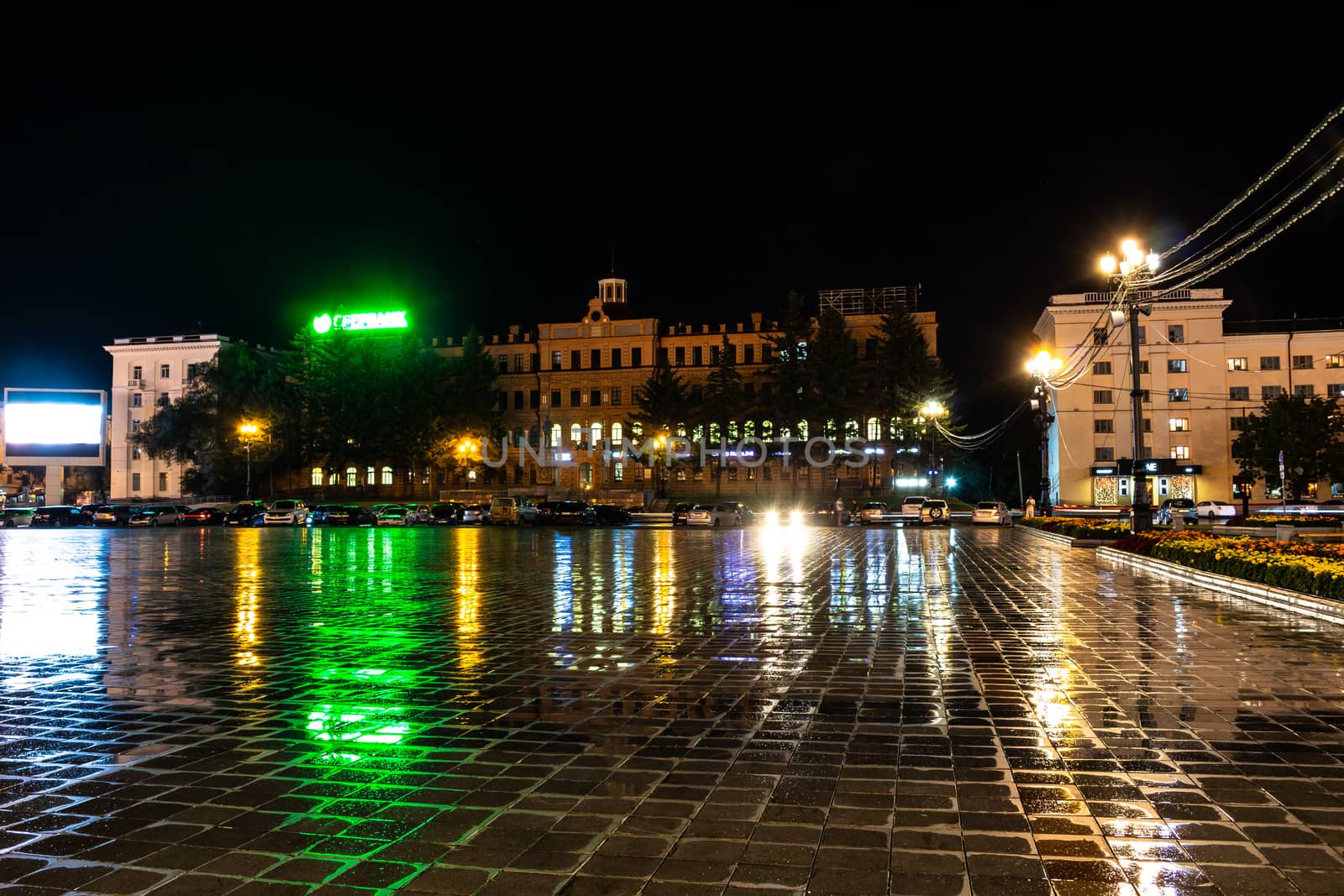 Night city landscape. The main square of the city of Khabarovsk in the light of lanterns, which are reflected in puddles after the rain just passed.