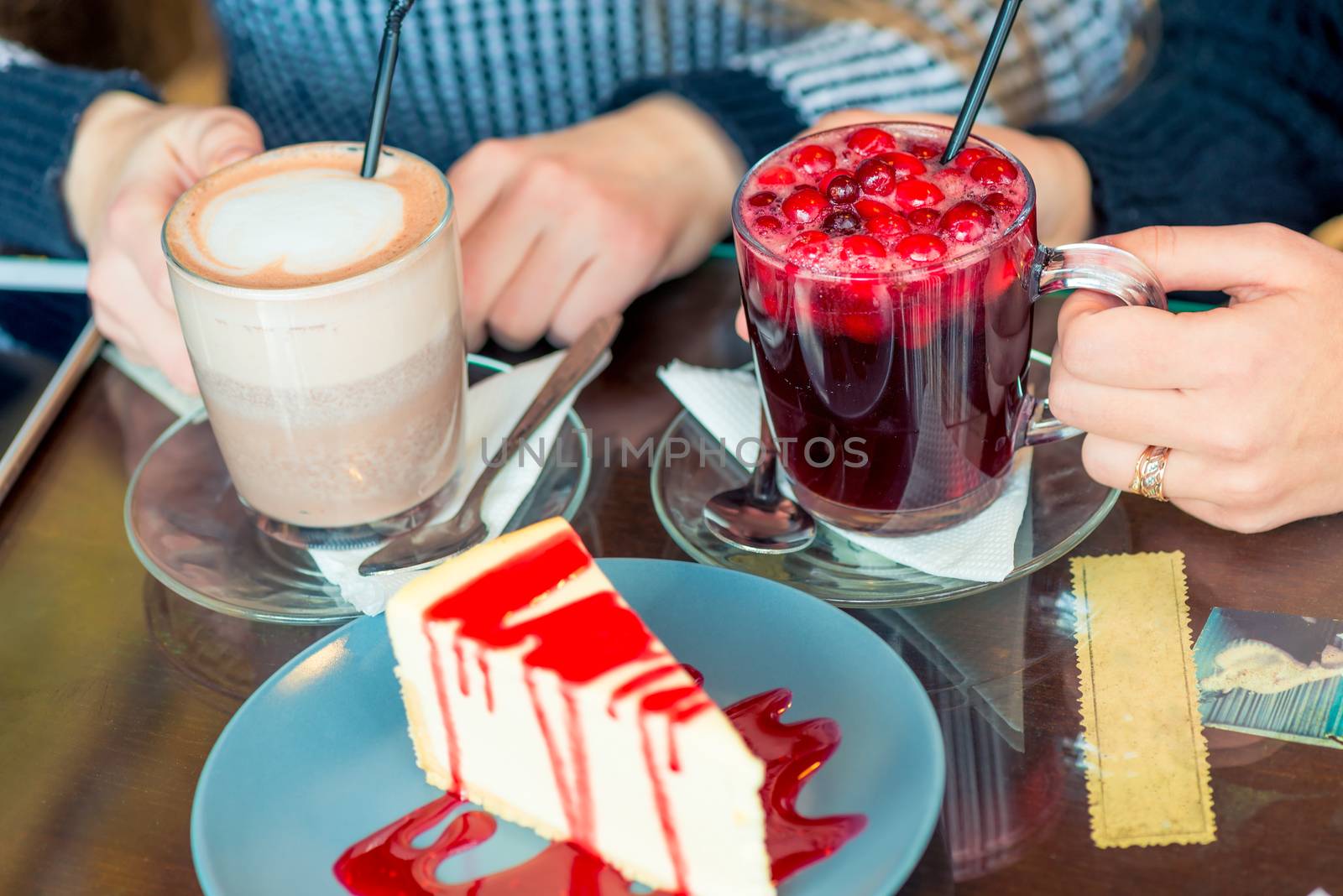 Female hands with hot drinks and sweet dessert on the table in a cafe