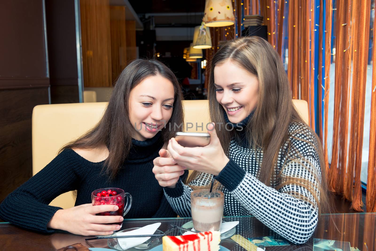 Girls friends with a phone breakfast in a cafe