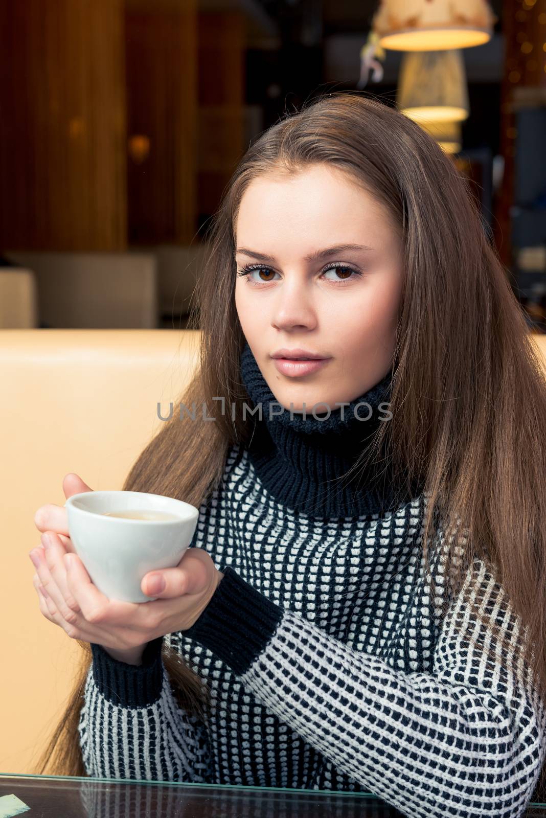 Cute brunette with a cup of tea in a cafe in a black sweater by kosmsos111