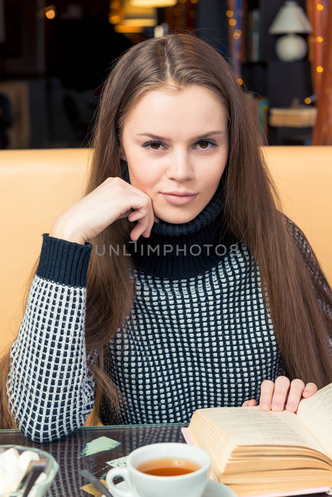 Smiling beautiful girl with book posing in cafe