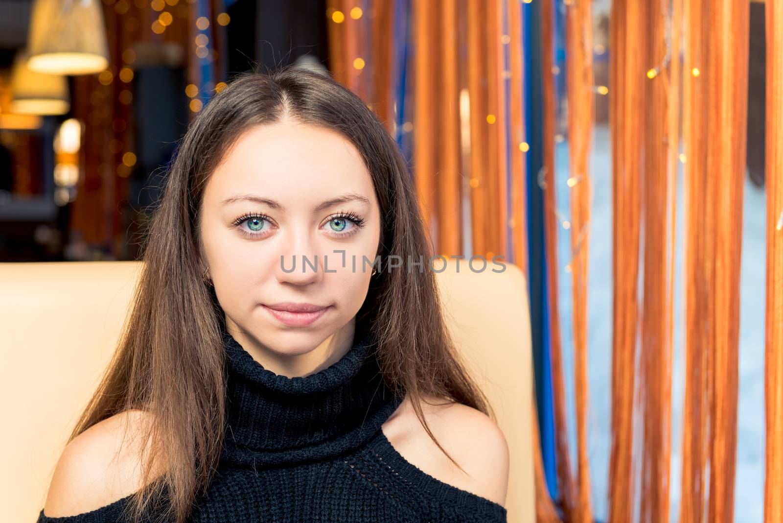 Portrait of a smiling girl with expressive eyes indoors, close-up