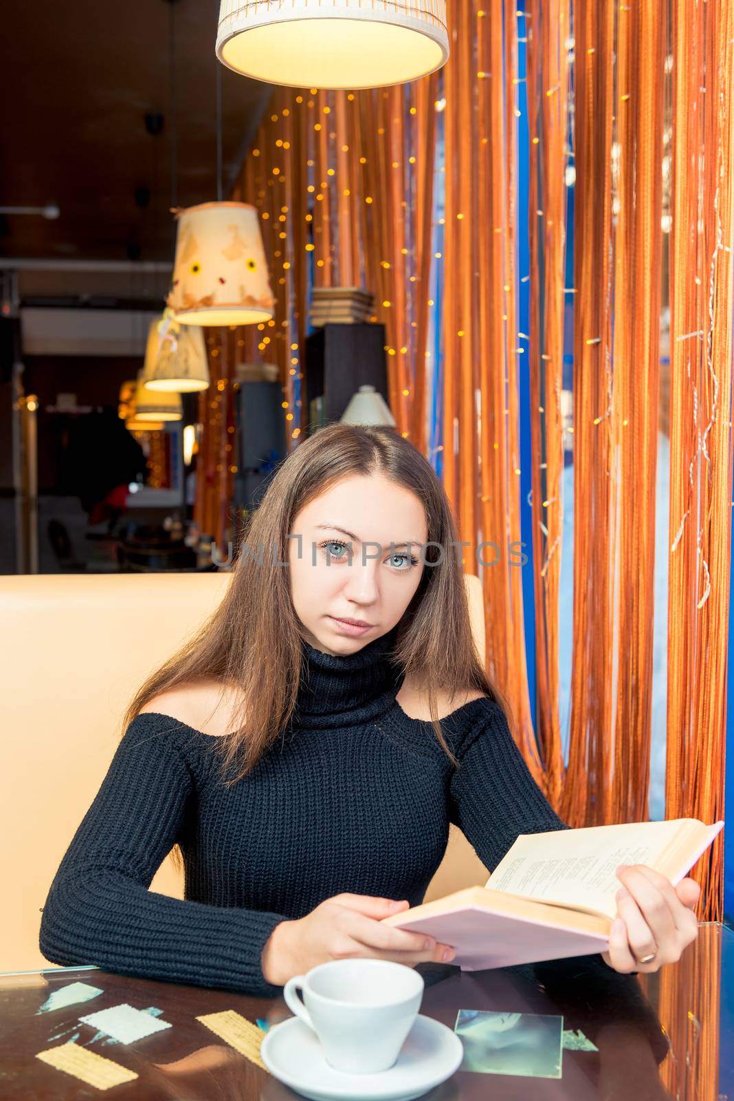 Portrait of a student with a thick interesting book in a cafe
