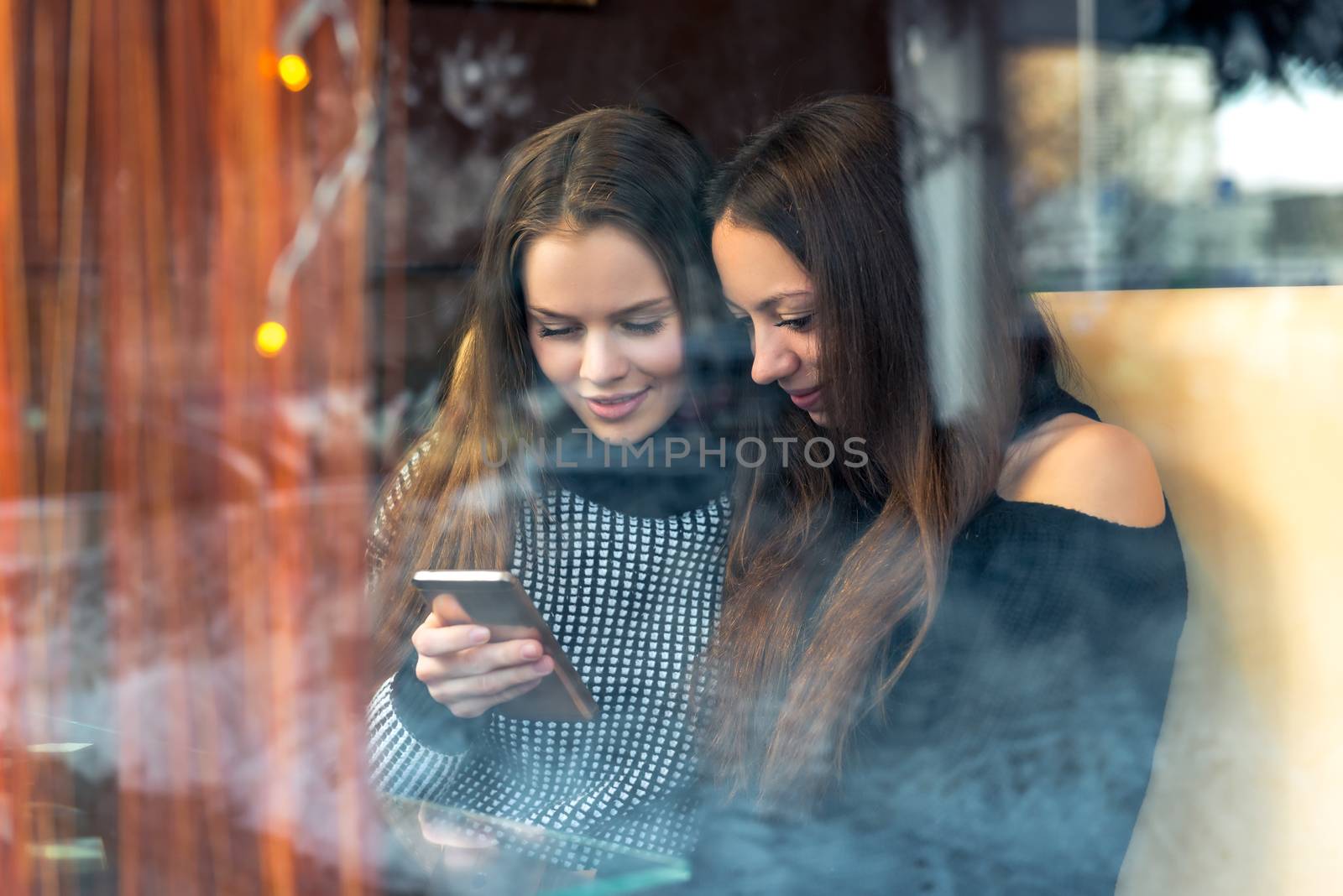 Girls with a phone, best friends in a cafe. Shooting behind the by kosmsos111