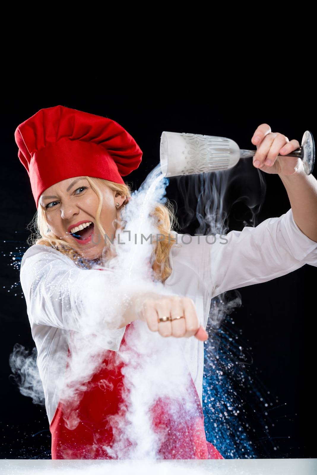 Animator woman cook doing an experiment with liquid nitrogen on a black background