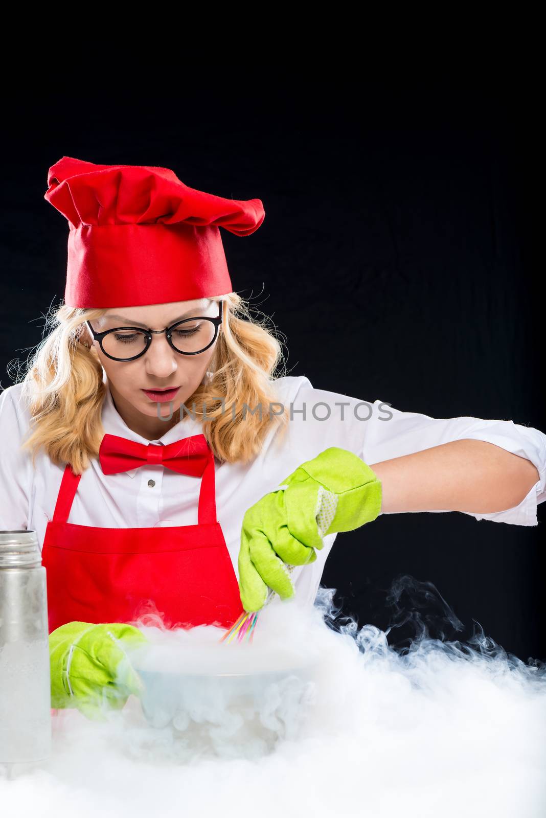 Woman animator cook doing experiments with liquid nitrogen, portrait on black background