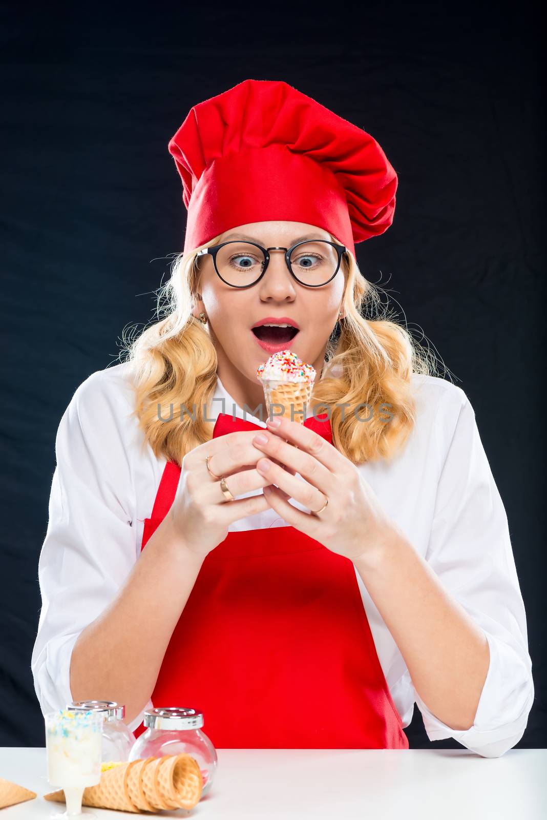 Surprised emotional chef with homemade ice cream, portrait is isolated on a black background