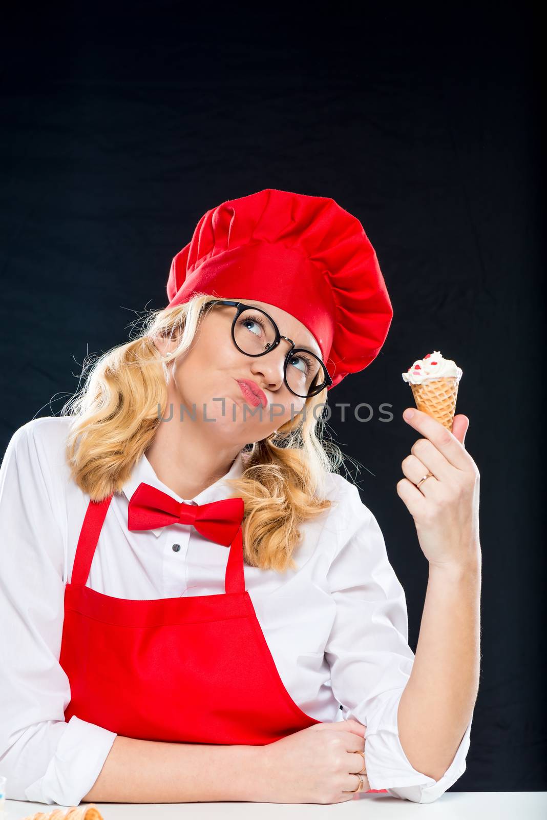 Thoughtful crazy cook posing with cream ice cream in a waffle cup