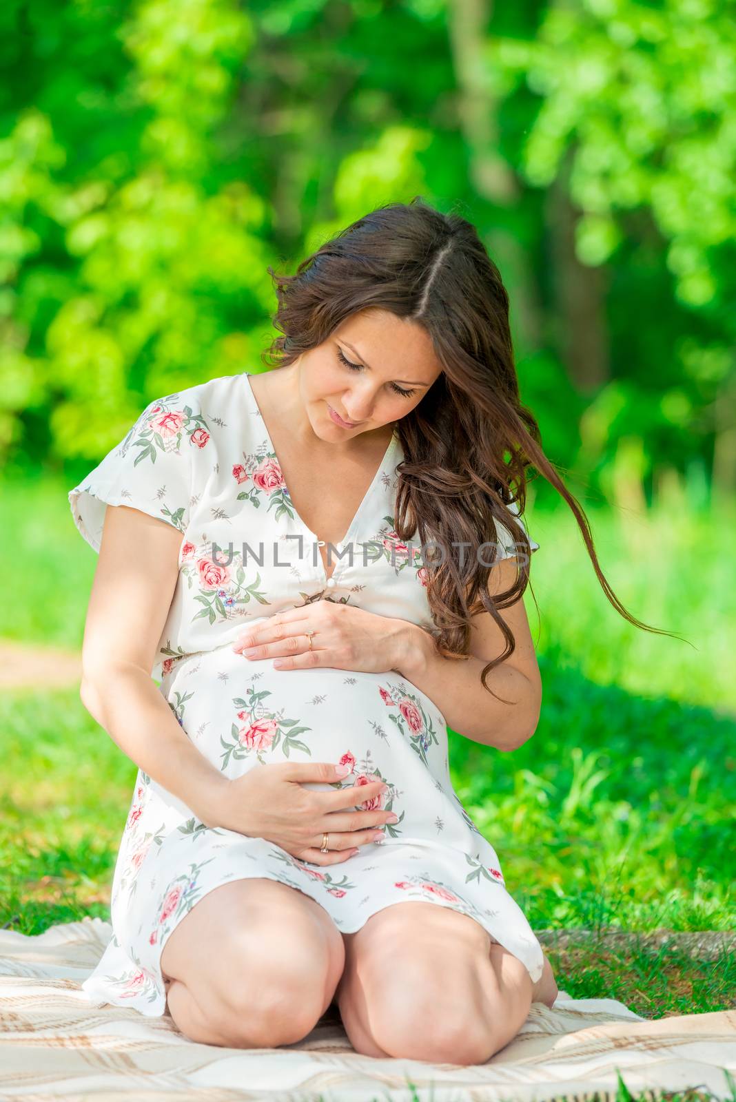 beautiful young pregnant woman in the park stroking her belly