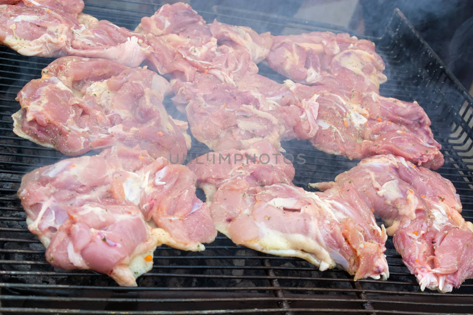 Raw pork chops on grill. Smoke rising from heated grill