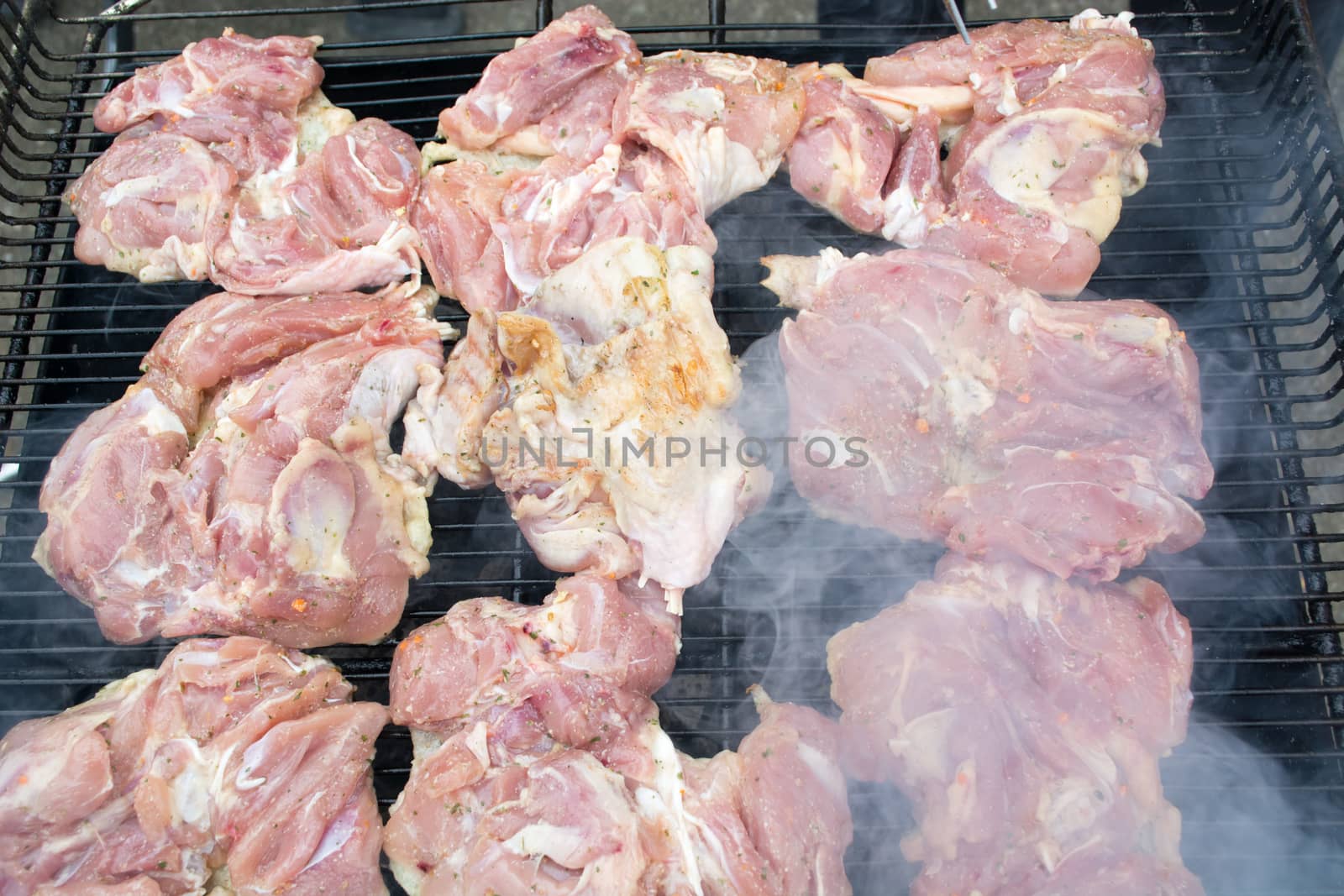 Raw pork chops on grill. Smoke rising from heated grill