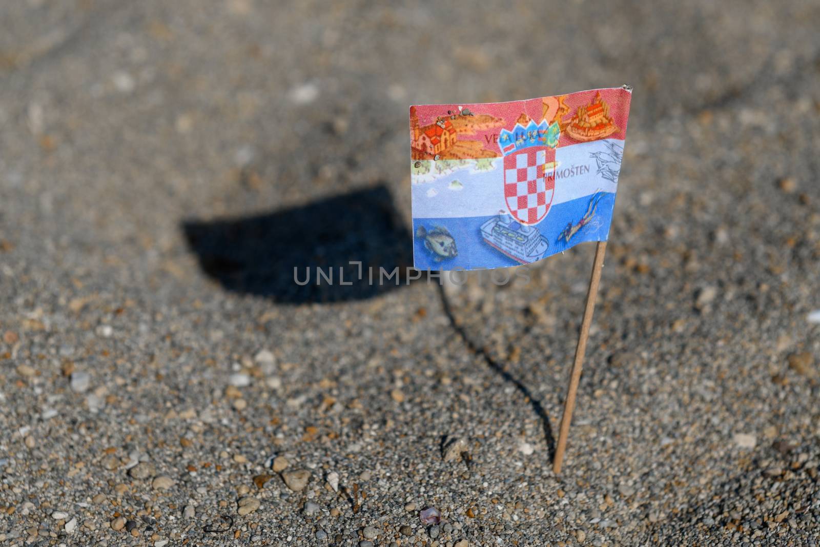 Touristic flag of Croatia picked in Sand on Beach by asafaric