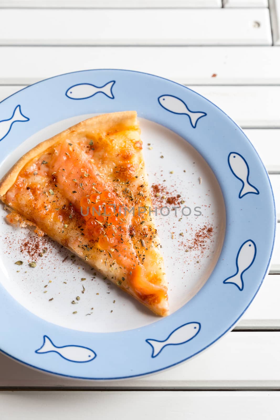 Pizza sliced with smoked salmon and egg on white wooden table