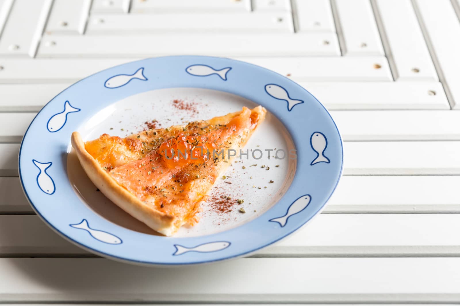 Pizza sliced with smoked salmon and egg on white wooden table